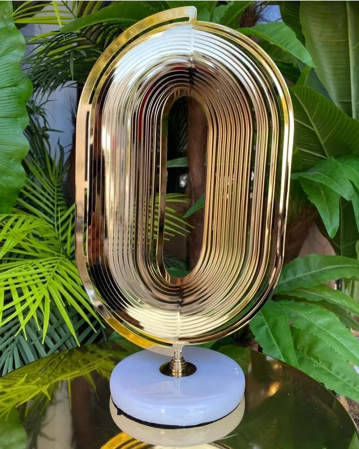 Gold plated oval spiral design on a white marble base