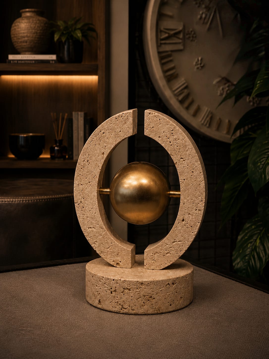 Travertine O-shaped sculpture with a rough, textured surface and brass interlocking details.