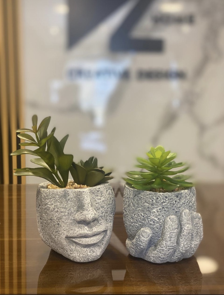 Decorative artificial succulents in artistic stone-style face and hand planters.